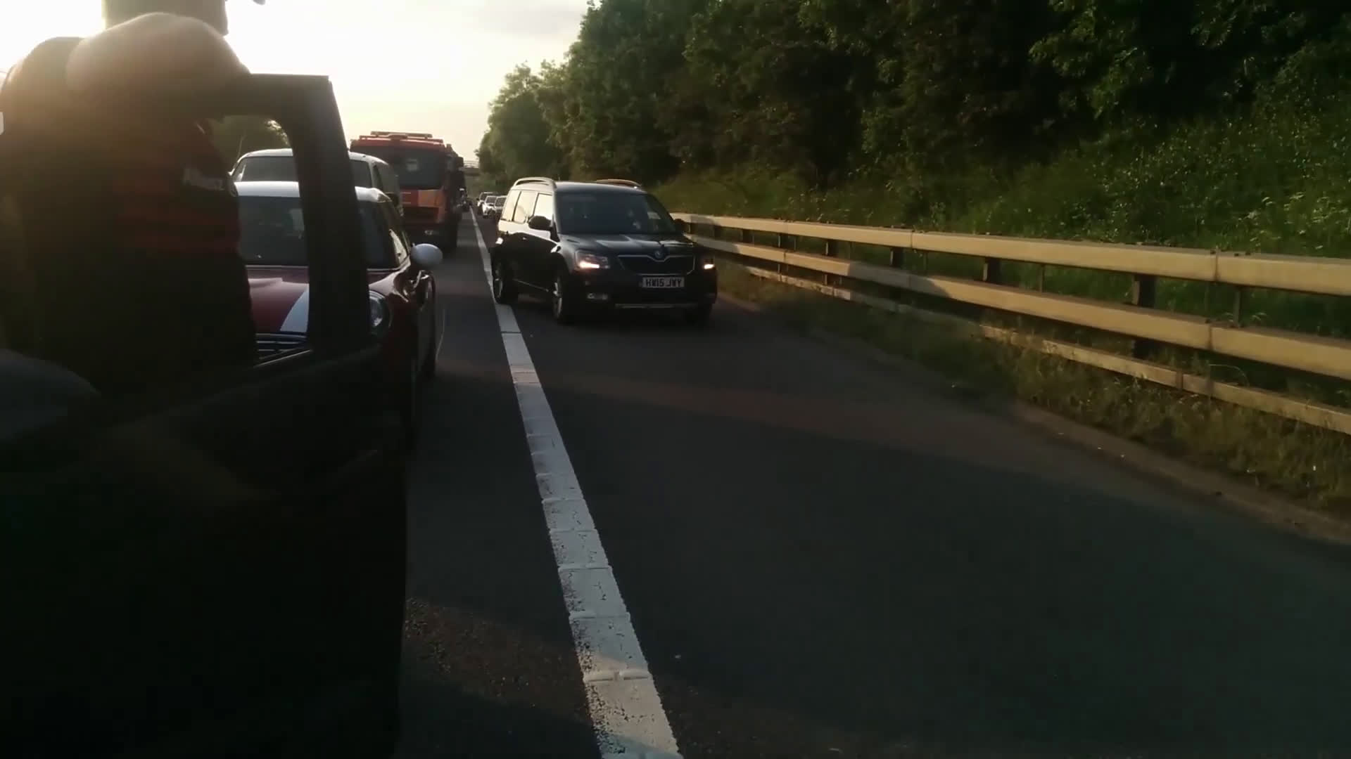 Stream of drivers using hard shoulder during motorway traffic